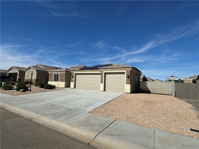 view of front facade with driveway, a residential view, an attached garage, roof mounted solar panels, and stucco siding