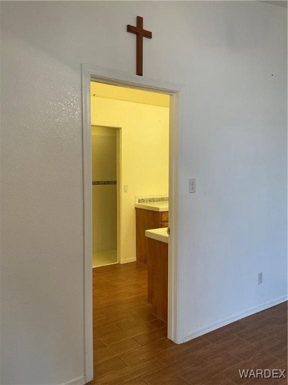 corridor with dark wood-style flooring and baseboards