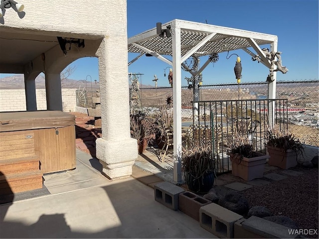 view of patio featuring fence and a hot tub