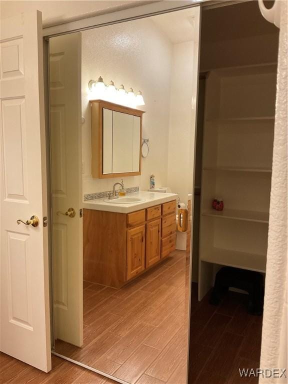 bathroom featuring a closet, vanity, and wood finished floors