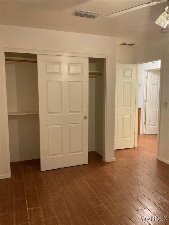 unfurnished bedroom with a closet, visible vents, and dark wood finished floors