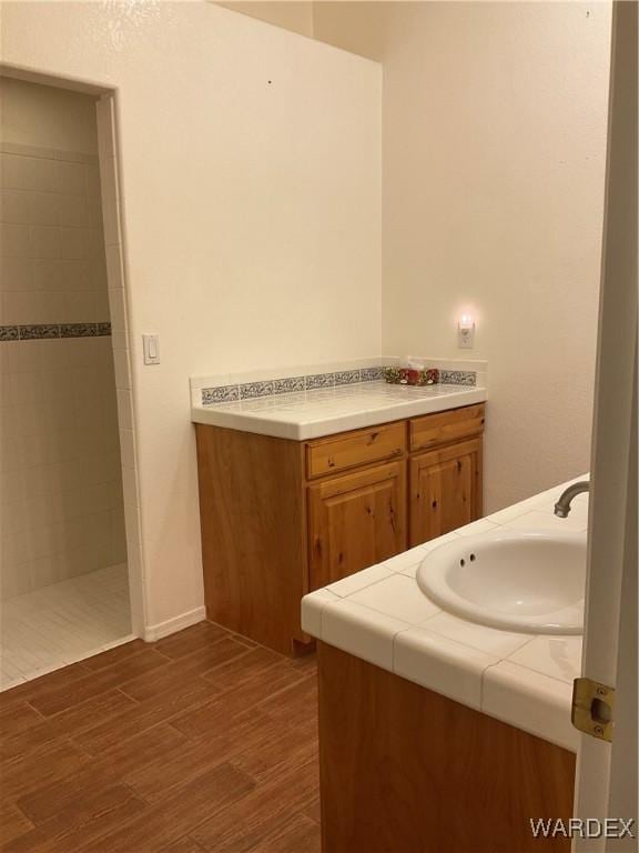 bathroom with walk in shower, wood finished floors, and vanity