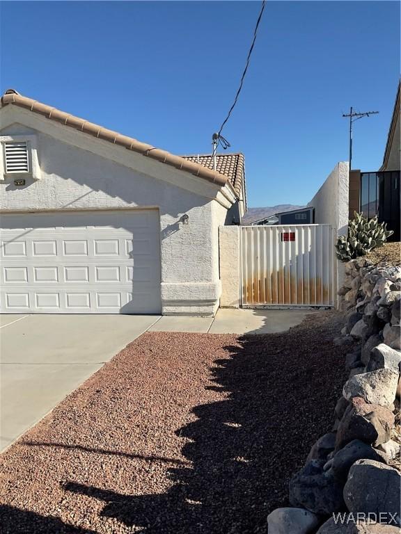 view of home's exterior featuring concrete driveway, a tile roof, and stucco siding