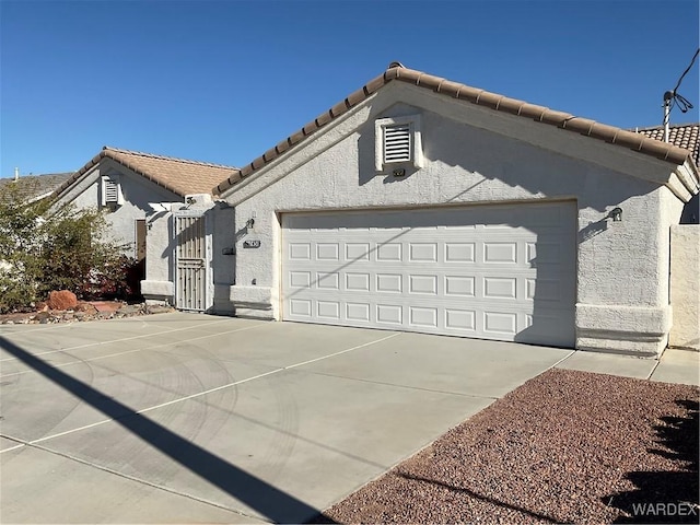 view of front facade featuring driveway, a tile roof, a garage, and stucco siding