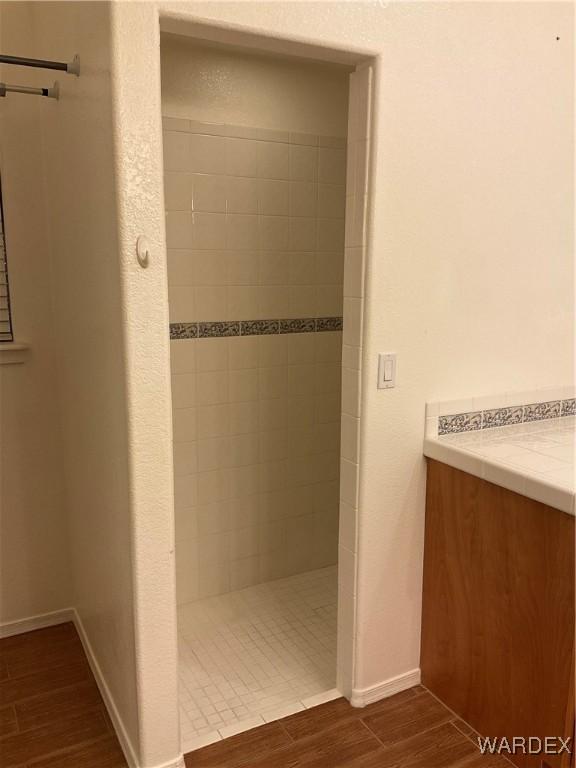 full bathroom featuring wood tiled floor, baseboards, and walk in shower