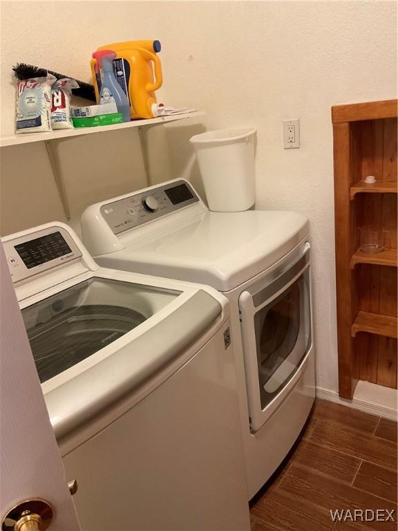 clothes washing area with dark wood-style floors, laundry area, and washer and dryer