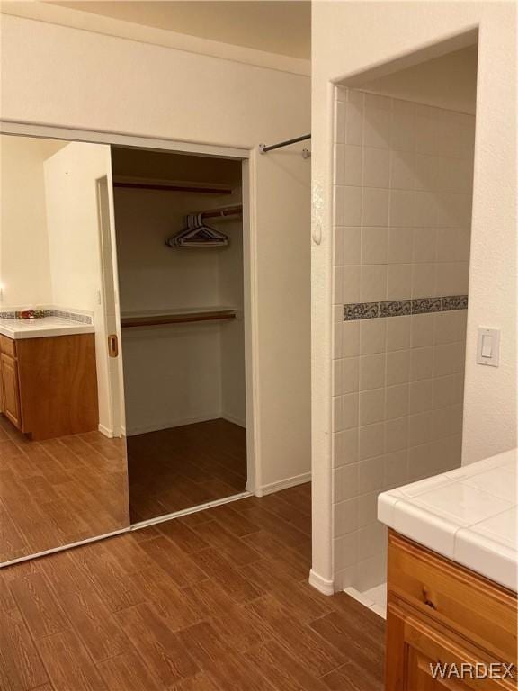 bathroom featuring a spacious closet, wood finished floors, and vanity