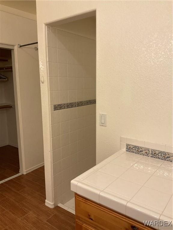 bathroom featuring a walk in closet and wood finished floors