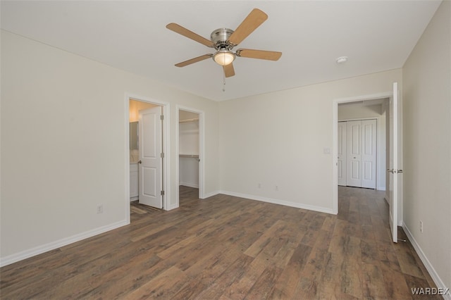 unfurnished bedroom featuring ceiling fan, baseboards, a walk in closet, and wood finished floors