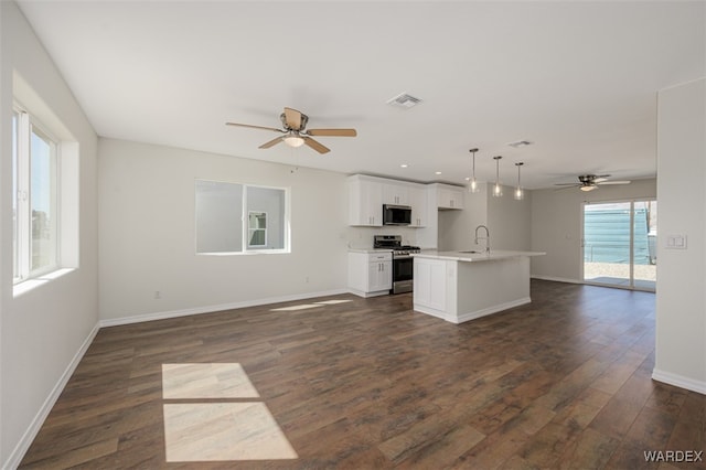 kitchen featuring dark wood-style flooring, stainless steel appliances, visible vents, open floor plan, and a sink