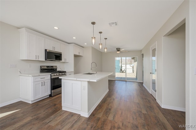 kitchen featuring dark wood-style flooring, stainless steel appliances, recessed lighting, white cabinetry, and a sink