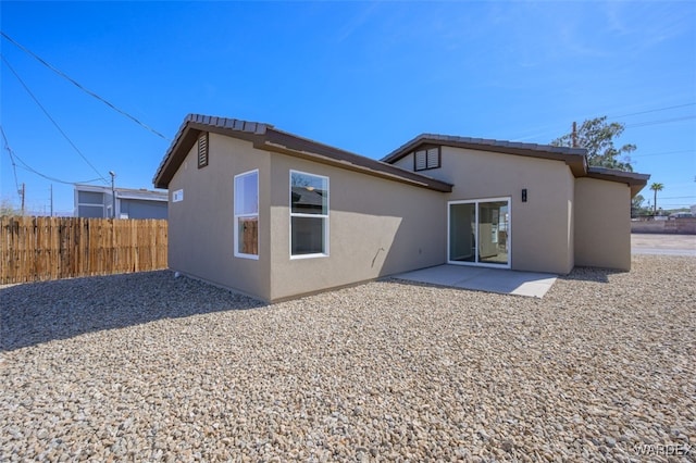 rear view of property with fence, a patio, and stucco siding