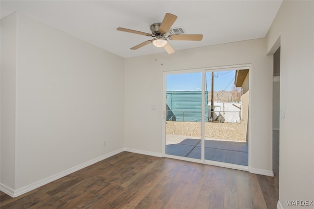 spare room with a ceiling fan, dark wood-style flooring, visible vents, and baseboards