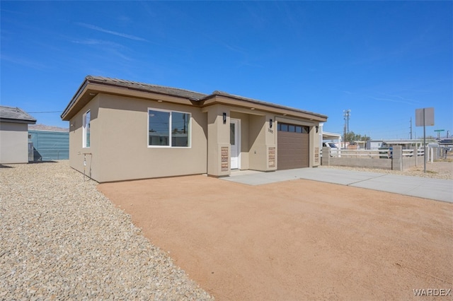 view of front of property featuring a garage, concrete driveway, fence, and stucco siding