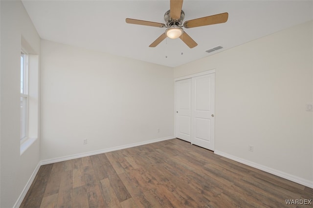 unfurnished room featuring a ceiling fan, wood finished floors, visible vents, and baseboards