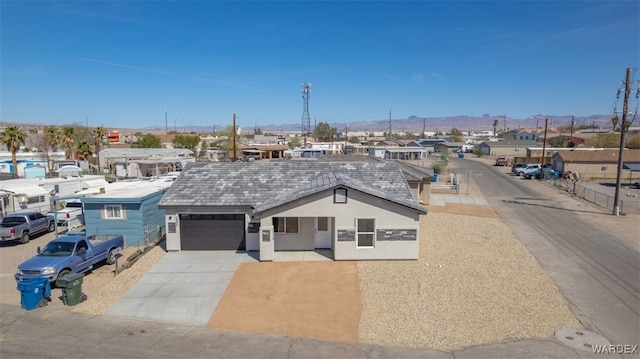 view of front facade with a mountain view, a garage, concrete driveway, a residential view, and stucco siding