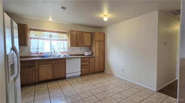 kitchen featuring light tile patterned floors, white appliances, a sink, and visible vents