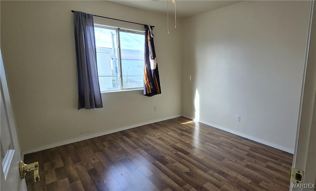 empty room with a wealth of natural light, dark wood-style flooring, and baseboards