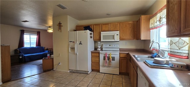 kitchen with light tile patterned floors, white appliances, a sink, visible vents, and light countertops