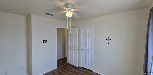 unfurnished bedroom featuring dark wood-style floors, a closet, visible vents, and a ceiling fan