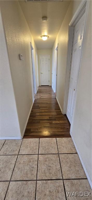 hallway with baseboards and tile patterned floors