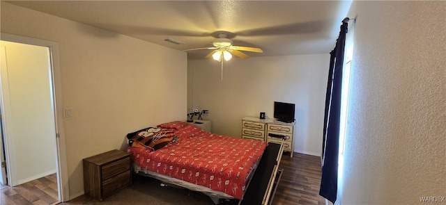 bedroom featuring baseboards, ceiling fan, visible vents, and wood finished floors