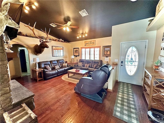 living room with a ceiling fan, visible vents, vaulted ceiling, and wood finished floors