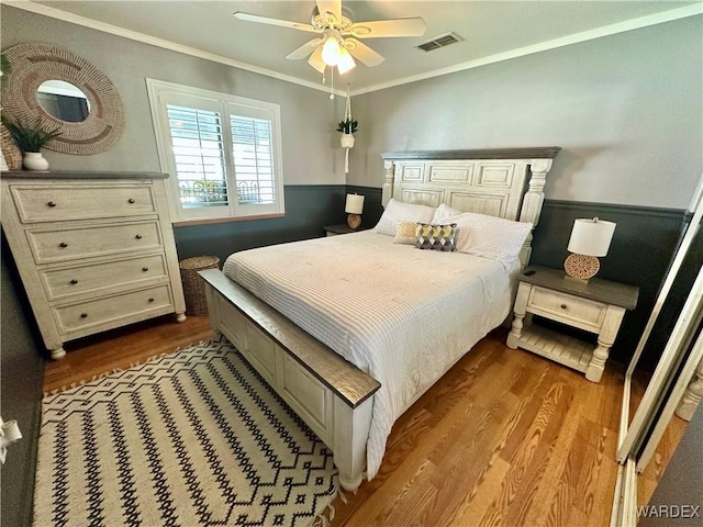 bedroom featuring crown molding, visible vents, dark wood-style flooring, and wainscoting