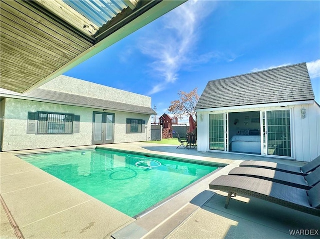 view of swimming pool featuring an outbuilding, a storage structure, french doors, a fenced in pool, and a patio area