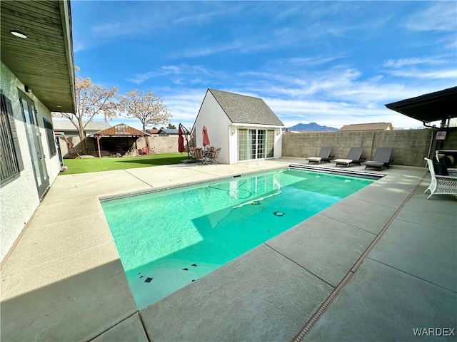 view of swimming pool with a fenced in pool, an outbuilding, a patio, an exterior structure, and a fenced backyard