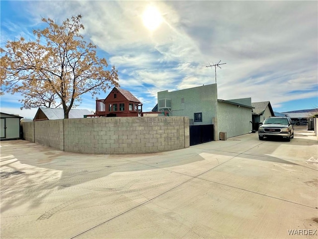 view of home's exterior with fence, cooling unit, an outdoor structure, a shed, and stucco siding