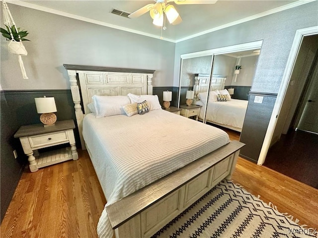 bedroom featuring a closet, wood finished floors, visible vents, and crown molding