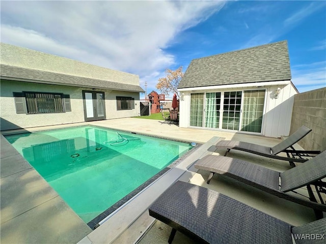 outdoor pool with an outbuilding, a patio, an exterior structure, and fence