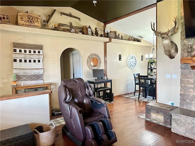 living area with lofted ceiling, arched walkways, wood finished floors, and visible vents