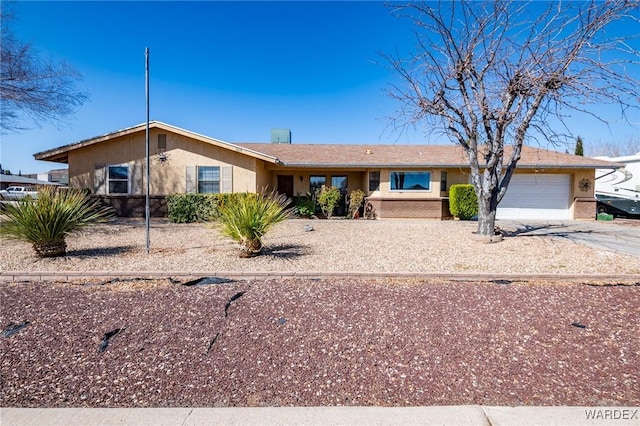 ranch-style house with brick siding, stucco siding, an attached garage, and driveway