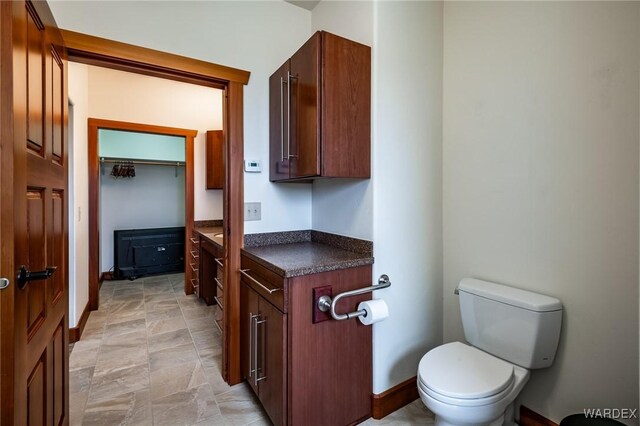 bathroom with toilet, baseboards, and a closet