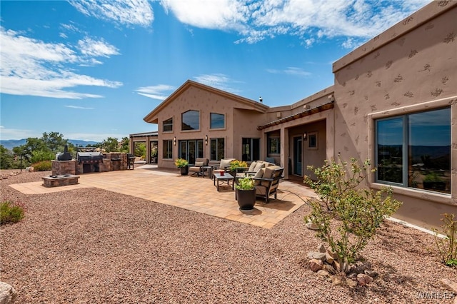 rear view of house featuring an outdoor hangout area, a patio, exterior kitchen, and stucco siding