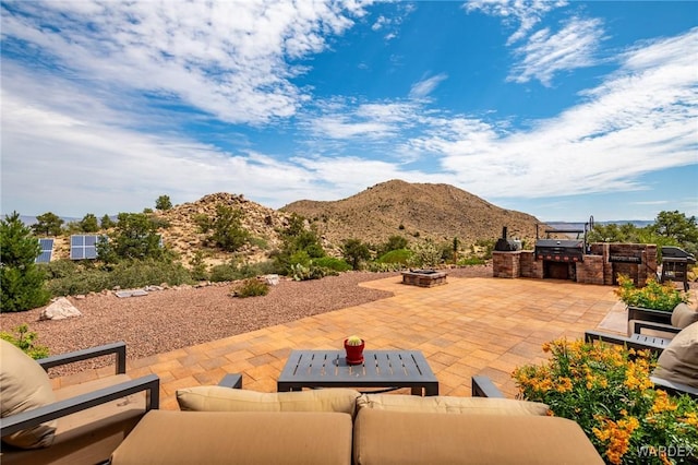 view of patio / terrace featuring a mountain view, an outdoor kitchen, and an outdoor living space with a fire pit