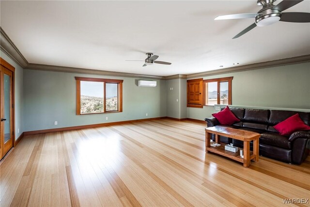 unfurnished living room featuring ornamental molding, a wall unit AC, light wood-style flooring, and baseboards