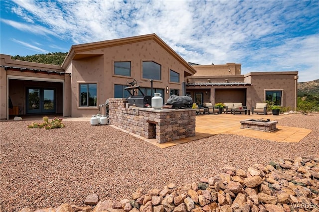 back of house with an outdoor fire pit, area for grilling, a patio, french doors, and stucco siding