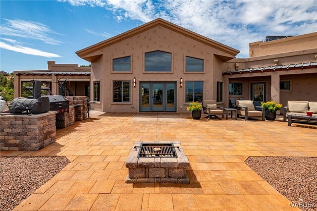 back of property with a fire pit, exterior kitchen, french doors, a patio area, and stucco siding