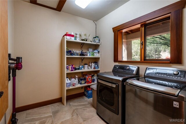 washroom with laundry area, washer and clothes dryer, and baseboards