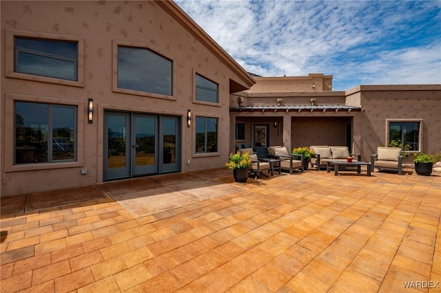 back of property featuring french doors, a patio, an outdoor living space, and stucco siding