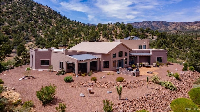 back of house with a patio area, a mountain view, and stucco siding