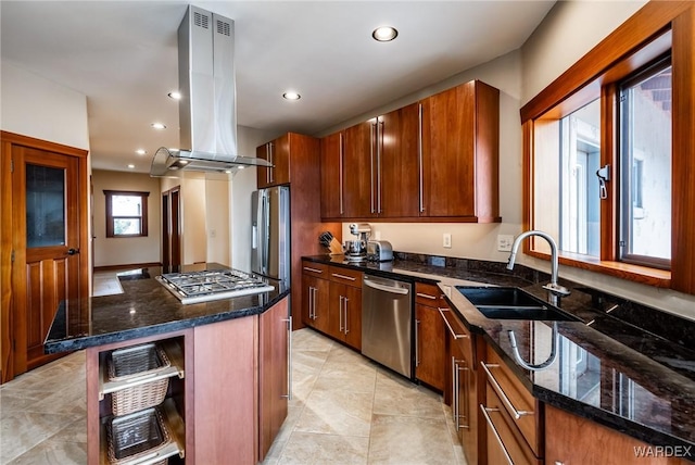 kitchen featuring a sink, a kitchen island, appliances with stainless steel finishes, dark stone countertops, and island exhaust hood