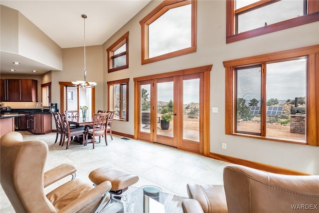 interior space with a wealth of natural light, a notable chandelier, a towering ceiling, and baseboards