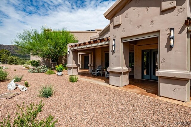 back of house with a tile roof and stucco siding