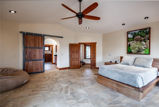 bedroom featuring arched walkways, a barn door, baseboards, vaulted ceiling, and stone finish floor