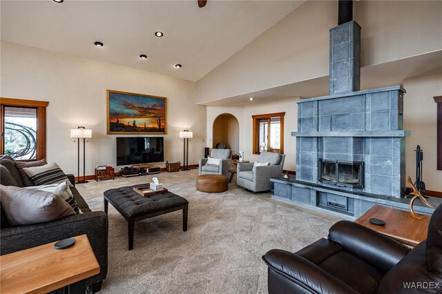 living area with high vaulted ceiling, plenty of natural light, a fireplace, and arched walkways