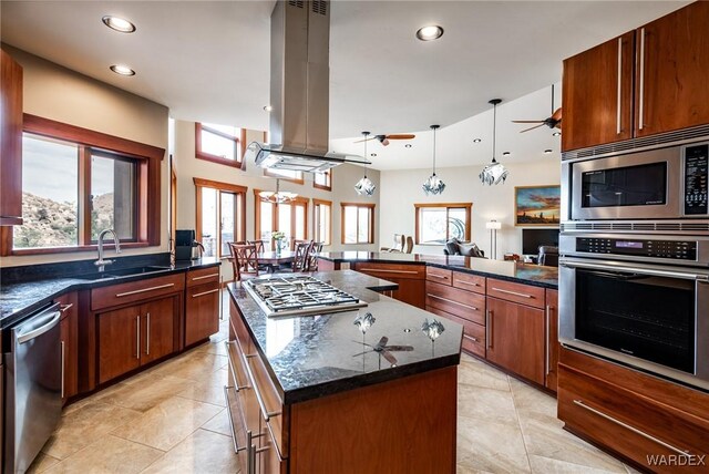 kitchen featuring hanging light fixtures, appliances with stainless steel finishes, a sink, a kitchen island, and island range hood